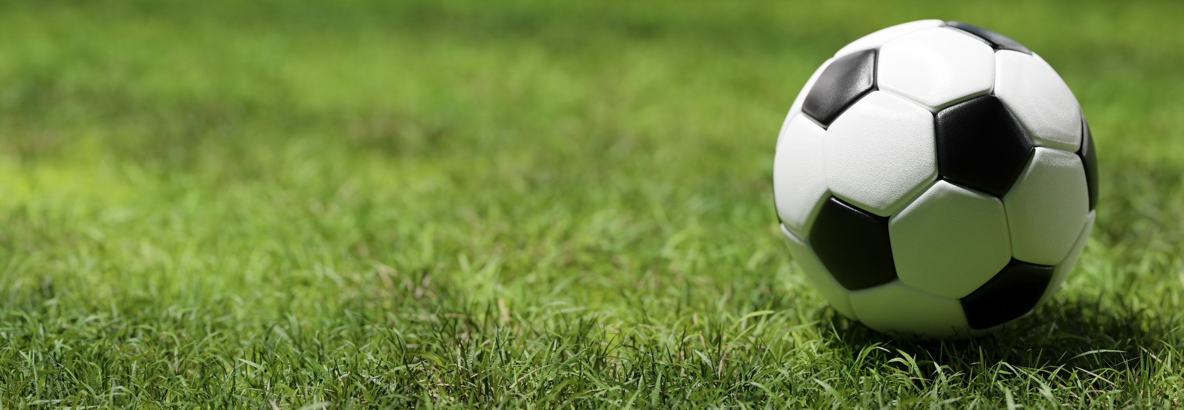 Football soccer ball on grass field in spotlight